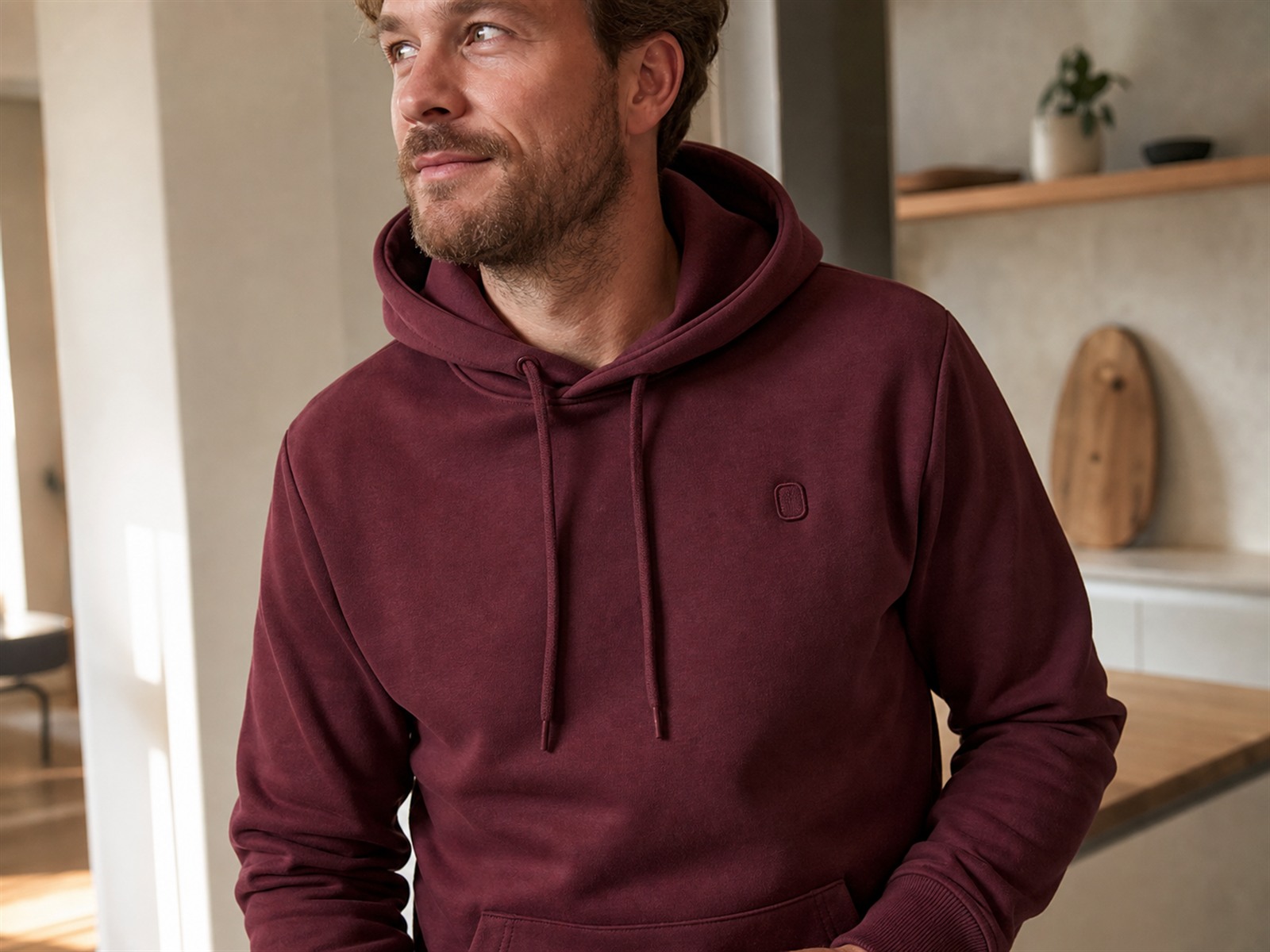 Mann trägt gern einen hochwertigen Bordeaux-Hoodie mit dezentem Logo-Stick – Mitarbeitergeschenke mit Qualität