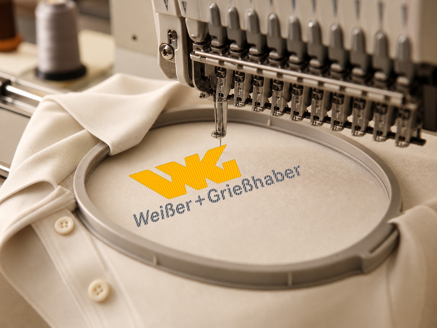 Stickmaschine stickt das Logo von Weisser und Grießhaber auf ein helles Poloshirt