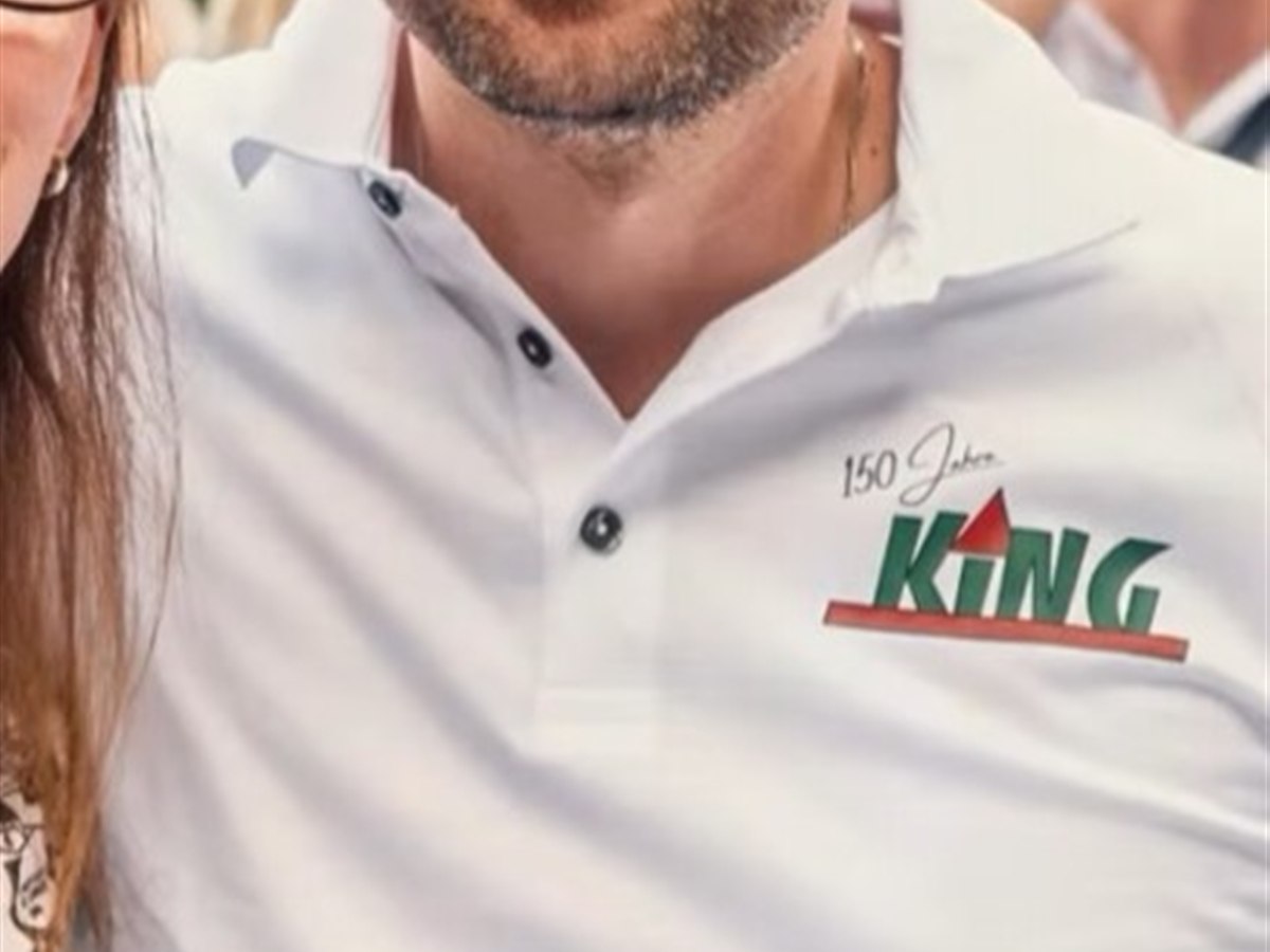 Gast des King-Bau-Jubiläumsfests trägt das weiße Polo mit 150-Jahre-Logodruck